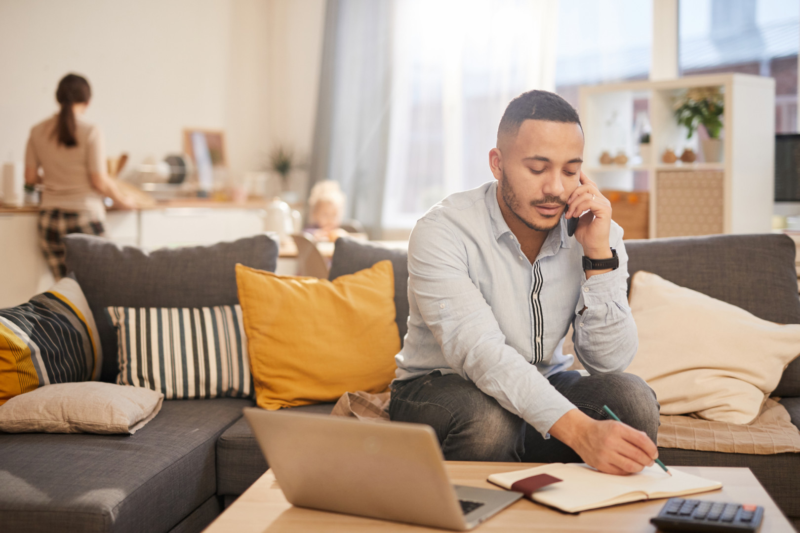 Man sitting on couch in home, on the phone.